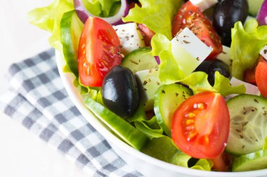 Kiraz domates, ruccola, roka, beyaz peynir, zeytin, salatalık, soğan ve baharat taze Yunan salatası yaptı. Sezar salatası ahşap arka plan üzerinde beyaz bir kase. Sağlıklı organik beslenme gıda kavramı.