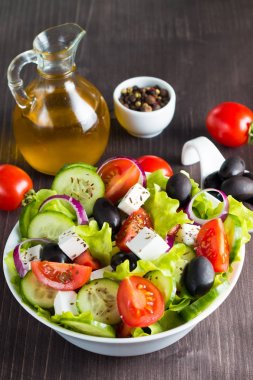 Kiraz domates, ruccola, roka, beyaz peynir, zeytin, salatalık, soğan ve baharat taze Yunan salatası yaptı. Sezar salatası ahşap arka plan üzerinde beyaz bir kase. Sağlıklı organik beslenme gıda kavramı.