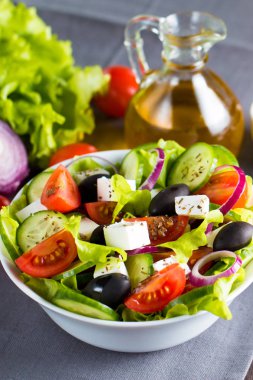 Kiraz domates, ruccola, roka, beyaz peynir, zeytin, salatalık, soğan ve baharat taze Yunan salatası yaptı. Sezar salatası ahşap arka plan üzerinde beyaz bir kase. Sağlıklı organik beslenme gıda kavramı.