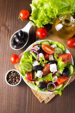 Kiraz domates, ruccola, roka, beyaz peynir, zeytin, salatalık, soğan ve baharat taze Yunan salatası yaptı. Sezar salatası ahşap arka plan üzerinde beyaz bir kase. Sağlıklı organik beslenme gıda kavramı.