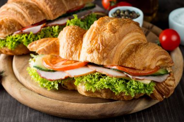 Taze kruvasan veya sandviç salata, jambon, jamon, jambon, salam, peynir, tavuk, domates ahşap arka plan ile. Sabah kahvaltı kavramı. Sağlıklı ve fast food.