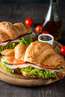 Taze kruvasan veya sandviç salata, jambon, jamon, jambon, salam, peynir, tavuk, domates ahşap arka plan ile. Sabah kahvaltı kavramı. Sağlıklı ve fast food.