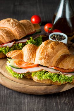 Taze kruvasan veya sandviç salata, jambon, jamon, jambon, salam, peynir, tavuk, domates ahşap arka plan ile. Sabah kahvaltı kavramı. Sağlıklı ve fast food.