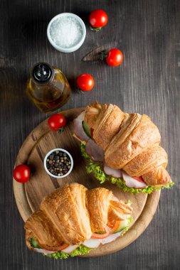 Taze kruvasan veya sandviç salata, jambon, jamon, jambon, salam, peynir, tavuk, domates ahşap arka plan ile. Sabah kahvaltı kavramı. Sağlıklı ve fast food.