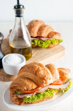 Taze kruvasan veya sandviç salata, jambon, jamon, jambon, salam, peynir, tavuk, domates ahşap arka plan ile. Sabah kahvaltı kavramı. Sağlıklı ve fast food.