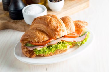 Taze kruvasan veya sandviç salata, jambon, jamon, jambon, salam, peynir, tavuk, domates ahşap arka plan ile. Sabah kahvaltı kavramı. Sağlıklı ve fast food.