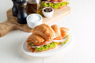 Taze kruvasan veya sandviç salata, jambon, jamon, jambon, salam, peynir, tavuk, domates ahşap arka plan ile. Sabah kahvaltı kavramı. Sağlıklı ve fast food.