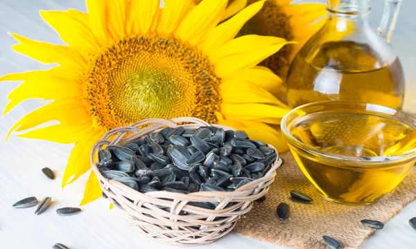 Sunflower oil and sunflower seeds in small sack on traditional rustic wooden background. Organic and eco food concept. Healthy food and fats.