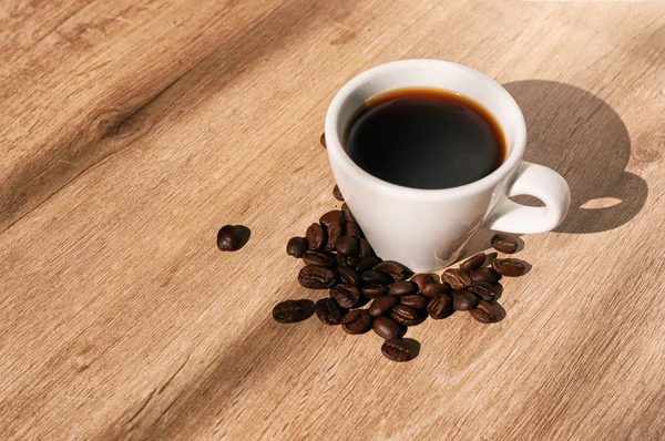Kávécsésze mellett kávébab, fa felületen, átlós nézet — Stock Fotó