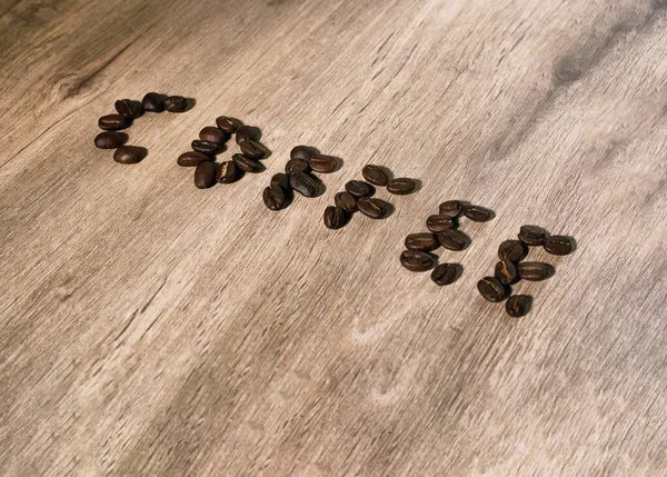 word coffee formed by coffee beans on a wood surface
