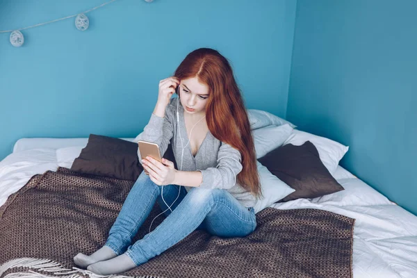 Happy modern red head young girl talking on video chat and sit a