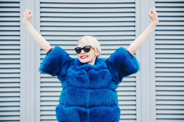 Woman happy concept. Successful woman in fur coat raising hands
