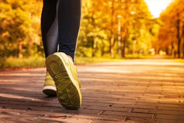 Athlete woman in running start pose on the city autumn park. Spo