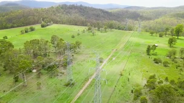 Aerial, high voltage power transmission lines in green countryside — 图库视频影像