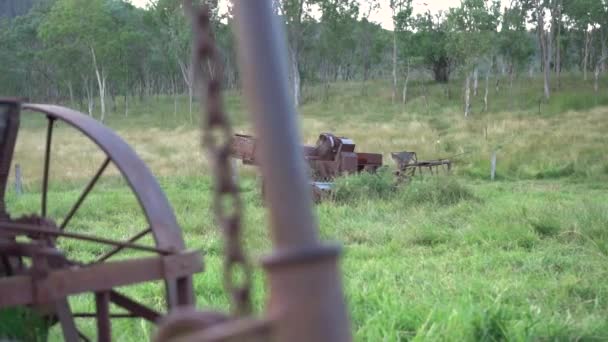 Ancienne machinerie agricole rouillée dans un enclos vert herbeux, glissière à gauche, lumière douce — Video