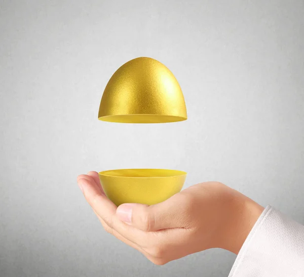 Mano sosteniendo huevos de oro —  Fotos de Stock