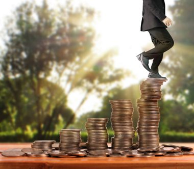 İşadamı, başarı ve yatırımı artıran madeni paraların üzerinde yürüyor