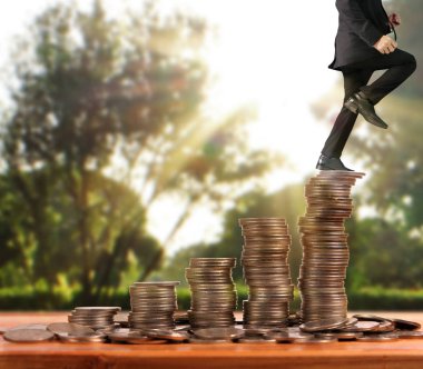 İşadamı, başarı ve yatırımı artıran madeni paraların üzerinde yürüyor