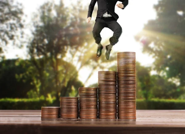 Businessman walk on stack of coins which grows success