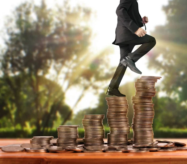 Businessman walk on stack of coins which grows success and investment