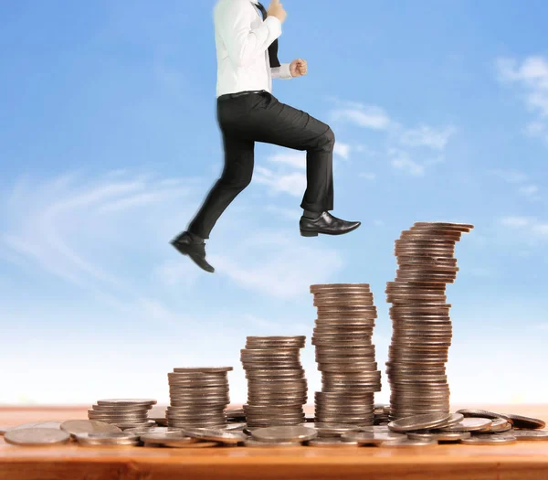 Бизнесмен ходит по стопке монет, которая растет успех — стоковое фото