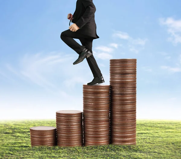 Businessman walk on stack of coins which grows success — Stock Photo, Image