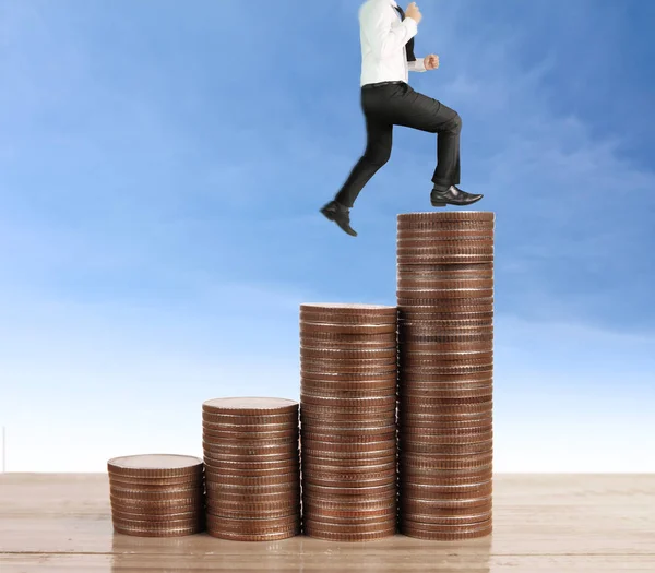 Businessman walk on stack of coins which grows success