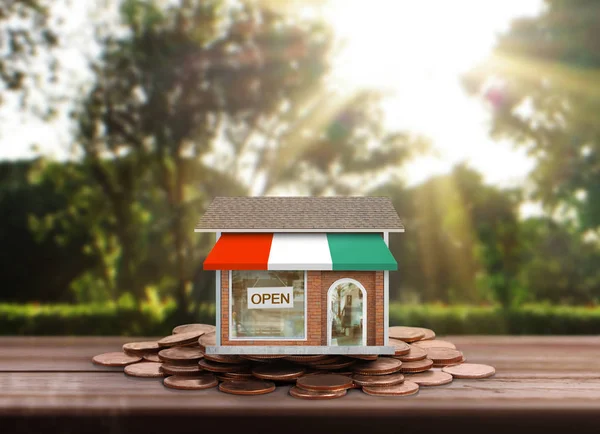 Маленький дом, стоящий на стопках монет — стоковое фото
