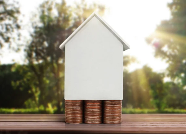 Pequeña casa de pie en pilas monedas — Foto de Stock