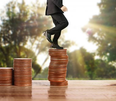 İşadamı, başarı ve yatırımı artıran madeni paraların üzerinde yürüyor