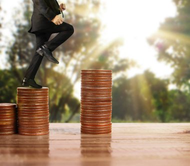 İşadamı, başarı ve yatırımı artıran madeni paraların üzerinde yürüyor