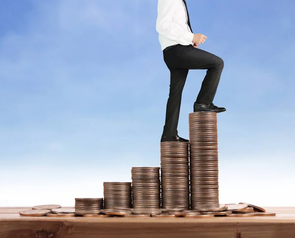 Businessman walk on stack of coins which grows success and investment