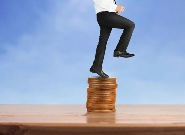 Businessman walk on stack of coins which grows success