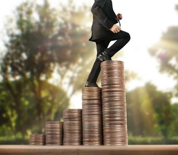 Businessman walk on stack of coins which grows success and investment