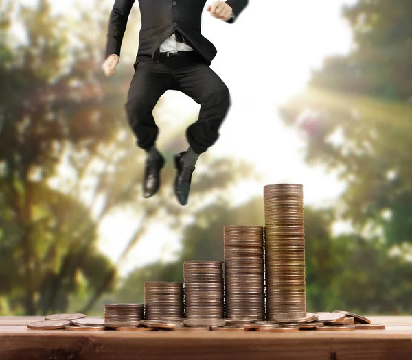 Businessman walk on stack of coins which grows success and investment