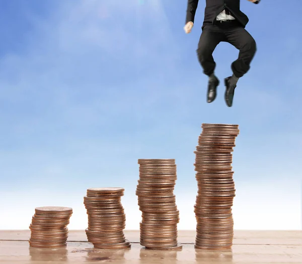 Businessman walk on stack of coins which grows success and investment