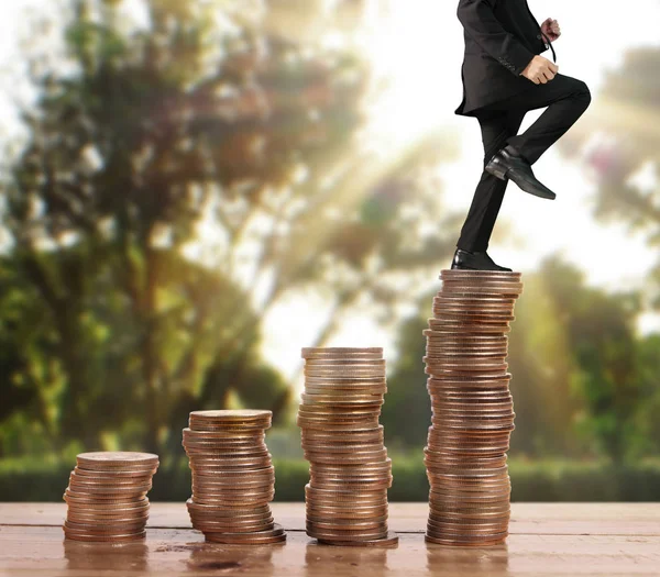 Бізнесмен ходить по стопах монет, які ростуть успішно — стокове фото