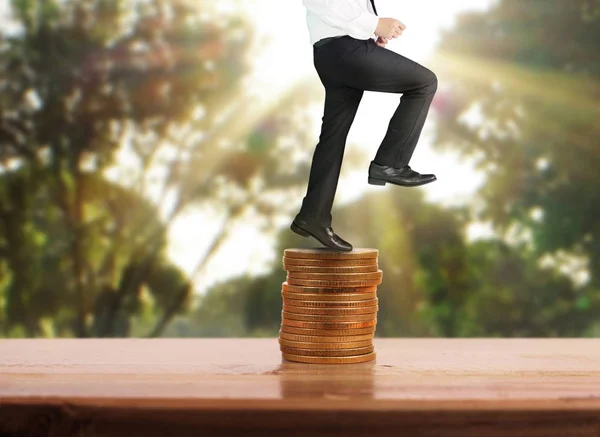 Businessman walk on stack of coins which grows success