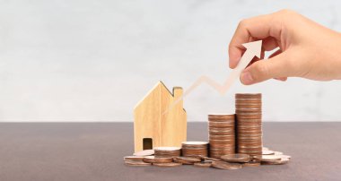 Tahta oyuncak ev ipoteği ev konsepti. Eldeki bozuk paralar B
