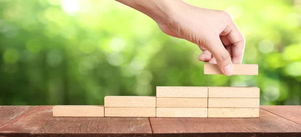 Trä block i handen stapling som steg trappa. Affärsidé gro — Stockfoto