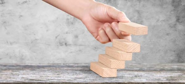 Деревянный блок в руке укладывается как ступенчатая лестница. Бизнес-концепция — стоковое фото