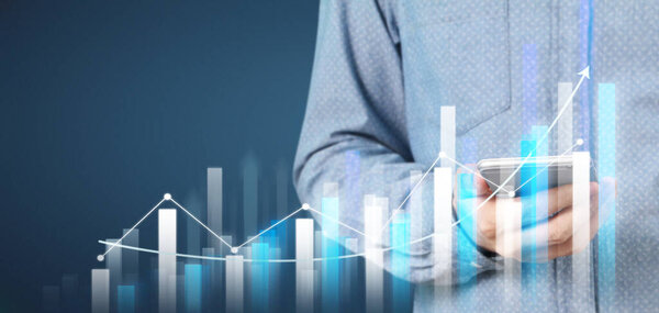 Hand holding smartphone device and touching screen. Stock exchange market concept. businessman trader looking on with graphs analysis candle