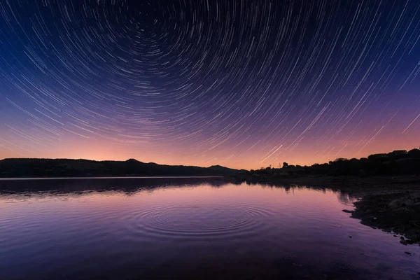 Star trails above ripples on a calm lake in Corsica at sunrise — Stock Photo, Image