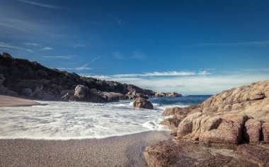 Dalgalar Corsica'deki / daki Calvi yakınındaki küçük bir kumlu koy üzerine yıkama