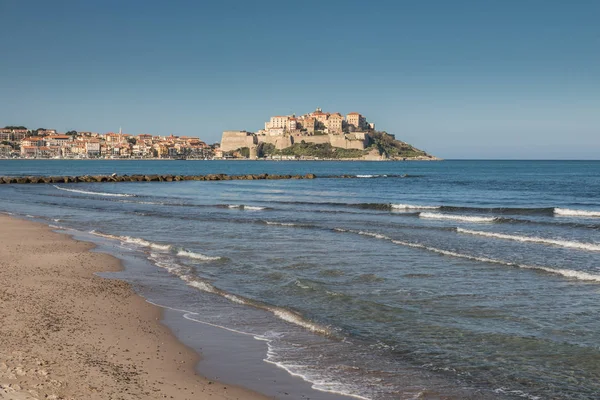 Olas cayendo sobre la playa de Calvi con Ciudadela y pueblo detrás —  Fotos de Stock