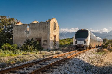 Train passing derelict station at Lumio in Corsica clipart