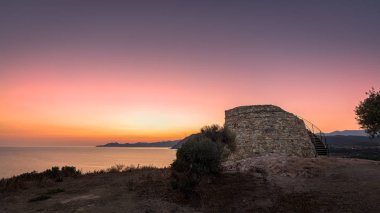 Güneş Lozari Corsica'deki / daki Ceneviz kulesinin arkasında doğuyor
