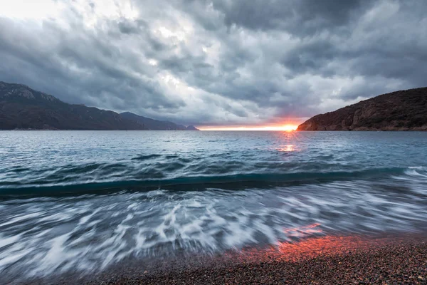 Sun setting under storm clouds at Bussaglia beach in Corsica — Stock Photo, Image