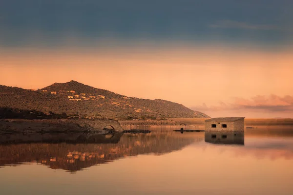 Verlaten stenen gebouw weerspiegeld in meer bij zonsondergang — Stockfoto