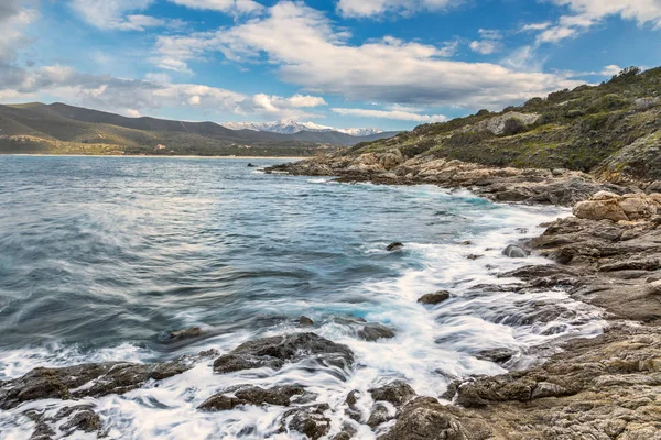 Rocky coast of Corsica and snow capped mountains — Stock Photo, Image